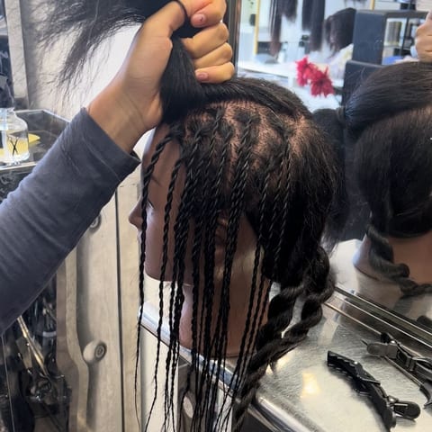 A child practising on a hairdresser block head